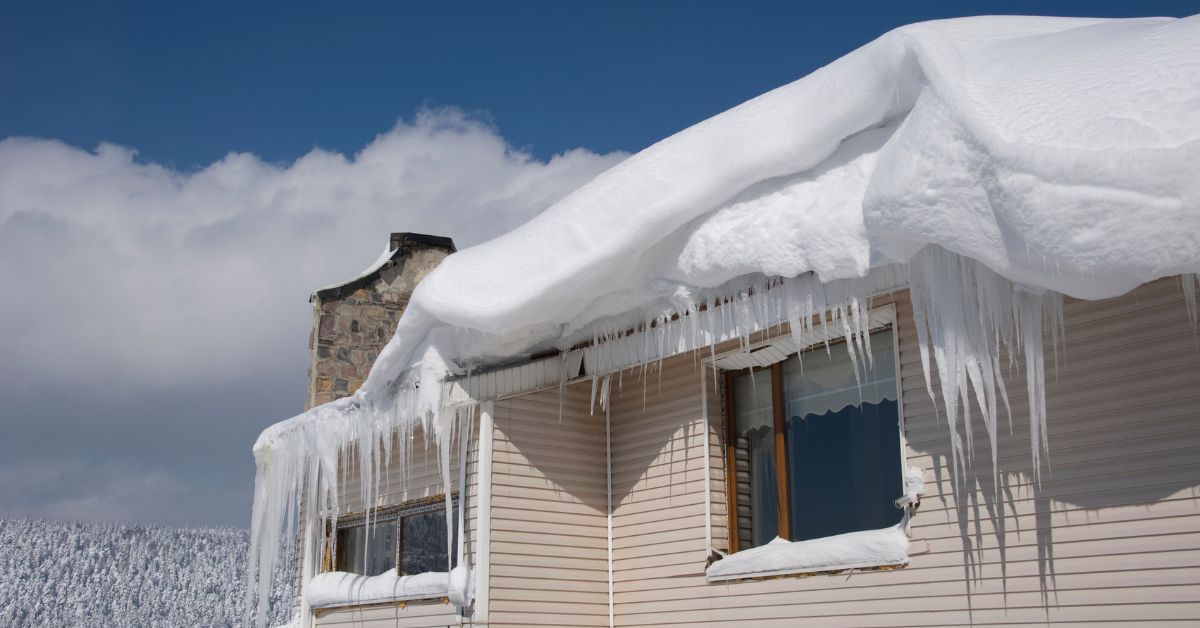 Several feet of snow on roof with large icicles.