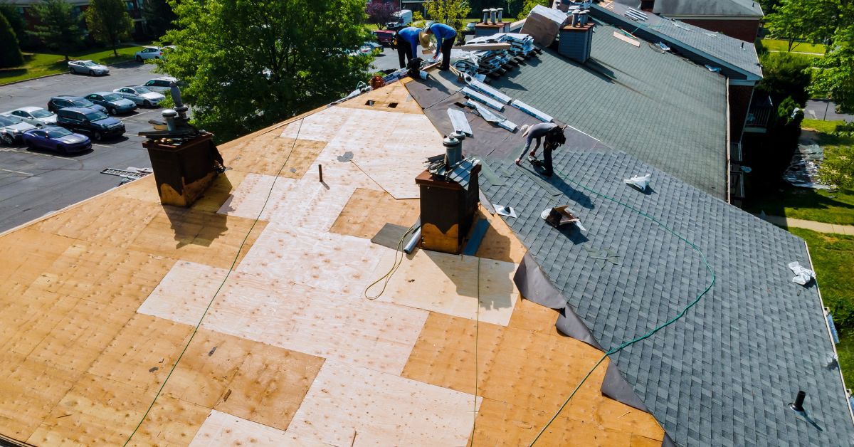 overhead shot of roofing workers doing roof repair and maintenance on a large roof