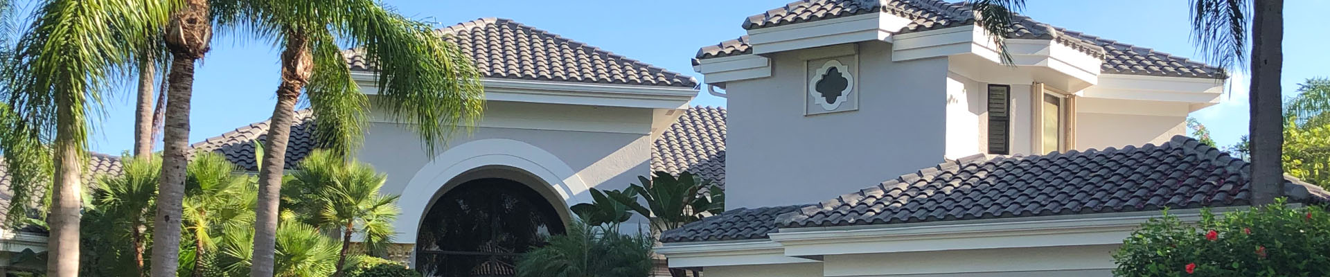 Flat black Spanish tile roofline on a completed Caldwell re-roof among South Florida palms