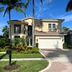 front of tan home with brown shingle roof