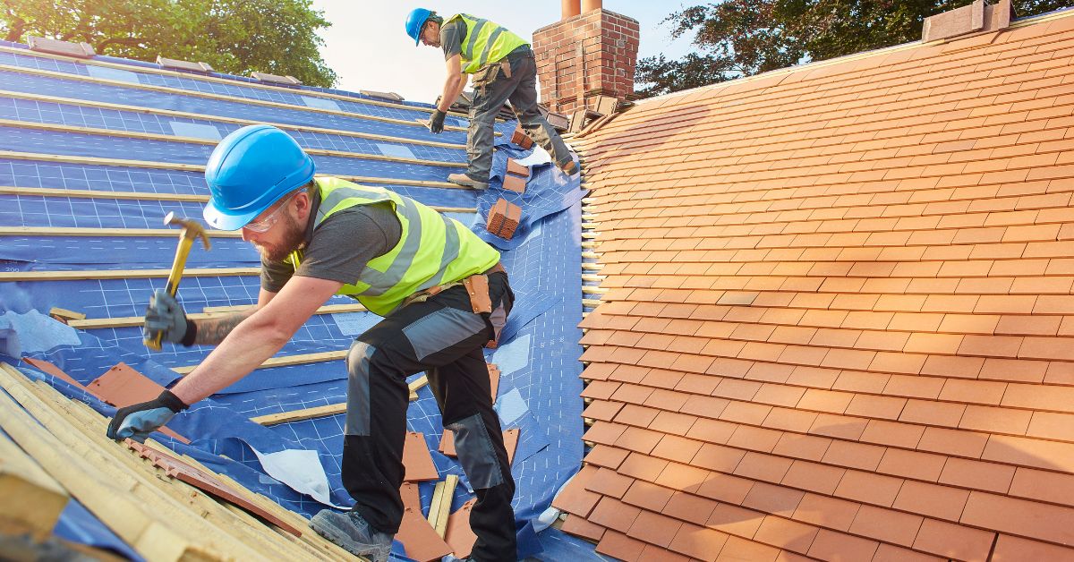 2 roof construction workers on a home roof doing a roof replacement