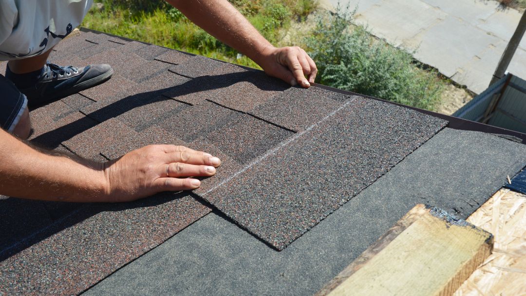Closeup shot of hands placing roof tlies for insurance roof replacement